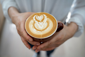 Latte art Coffee on hands at cafe
