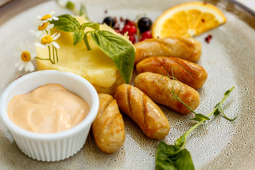 chicken sausages with mashed potatoes and sauce on a painted table