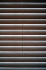 Close-up full frame inside view of closed horizontal window blinds with some sunlight shimmering through