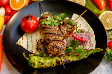 kebab with pita bread and grilled vegetables on a decorated table