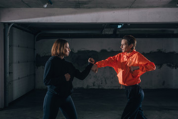 Two female athletes showing technical skills while practicing fighting in a garage