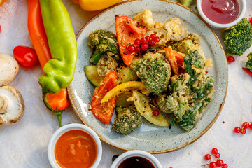 broccoli fried in breading with vegetables with sauces on a decorated table