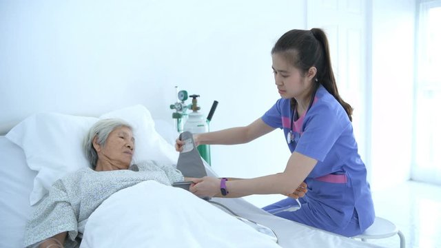 Medical concepts. Young nurse measuring the pressure of elderly patients in the hospital. 4k Resolution.
