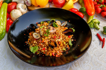 risotto rice with seafood, octopus mussels and vegetables with sauces on the decorated table