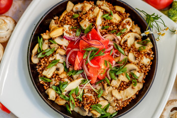 buckwheat with mushrooms, green onions and vegetables on the decorated table