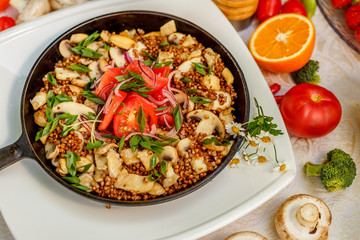 buckwheat with mushrooms, green onions and vegetables on the decorated table