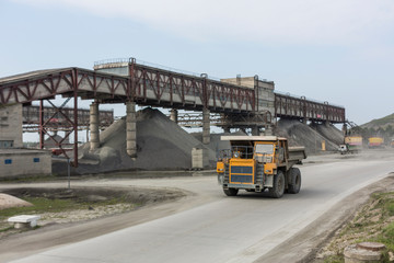 Fototapeta na wymiar Heavy mining truck driving through opencast on background of granite production