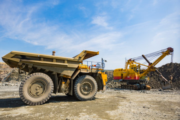 A mining excavator loads a heavy truck with granite rock huge machines