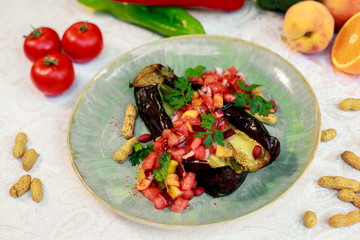 Healthy food, baked eggplant with vegetables, peppers and tomatoes on a white table