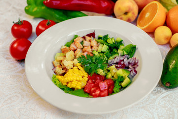 Healthy food, salad with shrimps, tomatoes, corn and avocado on a white table