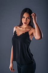 Portrait of a beautiful female model looking serious at the camera while touching her brunette hair