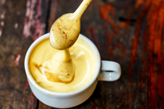 Top view a cup of Giang egg coffee  on wood background. Vietnamese coffee in Ha Noi, Vietnam. Eggs are beaten with coffee, hot drink or with ice