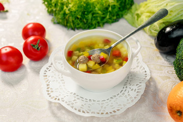 soup with meat balls, potatoes and vegetables in a white plate on a white table