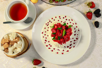 Pavlova dessert with cream mint and strawberry in a white plate on a white table