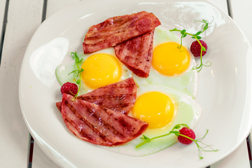 fried eggs with bacon bacon on a white plate. Breakfast