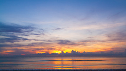 The blue sky with the light of the rising sun or the sunset is above the sea.