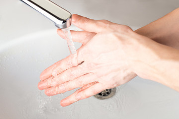 Washing hands under a stream of water  in the bathroom over the sink. Close-up of men's hands. Coronavirus, Covid-19