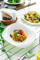 Italian pasta with cheese and vegetables on a white plate