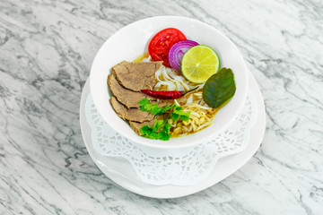 Asian food, noodle soup with beef and vegetables on a white plate, beautiful serving