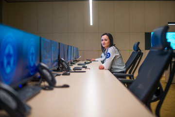 Fototapeta premium Female security guard sitting and monitoring modern CCTV cameras in surveillance room.