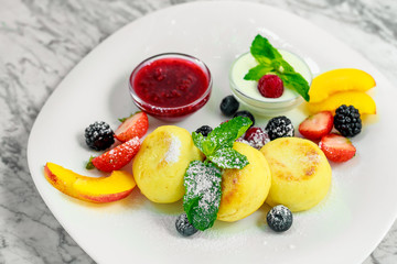 cottage cheese pancakes with fruit and jam on a white plate