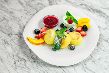 cottage cheese pancakes with fruit and jam on a white plate