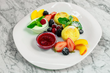 cottage cheese pancakes with fruit and jam on a white plate