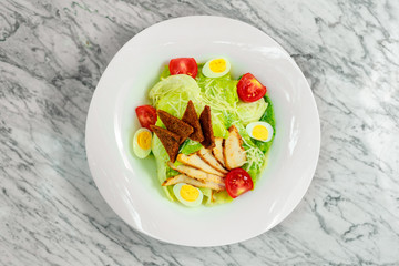 salad with chicken breast slices and vegetables on a white plate, beautiful serving
