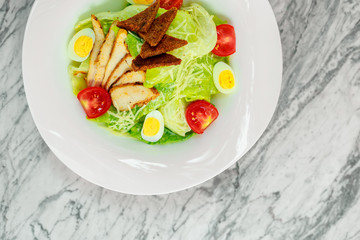 salad with chicken breast slices and vegetables on a white plate, beautiful serving