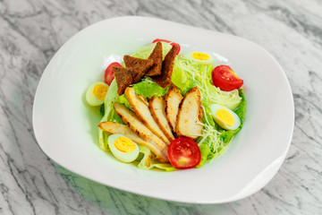 salad with chicken breast slices and vegetables on a white plate, beautiful serving