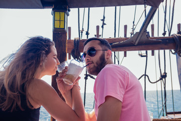 Obraz na płótnie Canvas Young couple in love drinking coffee on a boat and enjoying the sea