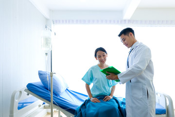 Asian male Doctor explaining diagnosis to female patient. Doctor discussing test results with patient.  test result was not infected with the coronavirus,hospital/ coronavirus and COVID-19 concept.