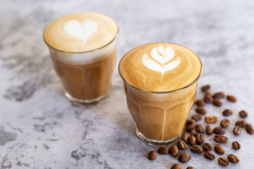 two hot latte coffee in glass with roasted coffee bean on white table background.