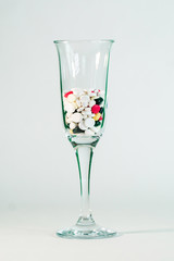 Covid-19. Champagne glass filled with medical pills stands on a white background