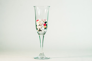 Covid-19. Champagne glass filled with medical pills stands on a white background