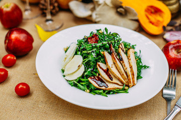 Autumn table setting with pumpkins. Thanksgiving dinner. Salad with chicken breast, cheese and arugula