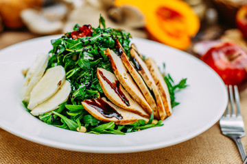 Autumn table setting with pumpkins. Thanksgiving dinner. Salad with chicken breast, cheese and arugula