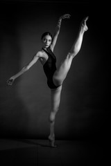 black and white dramatic vintage portrait of a girl, dancing ballerina in a black bodysuit in the Studio on gray background
