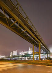 Night scene with illuminated petrochemical production plant and pipeline overpass, Antwerp, Belgium.