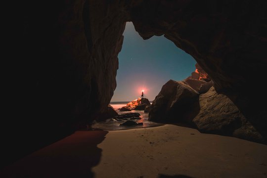 Man Holding Glowing Light Standing On Rock At Night