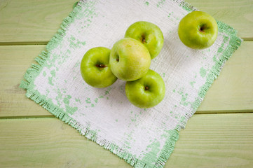 Ripe green apples on a light green painted wooden surface, illuminated by sunlight from a window through curtains. Background for fruits. Black and white drawing with natural light.
