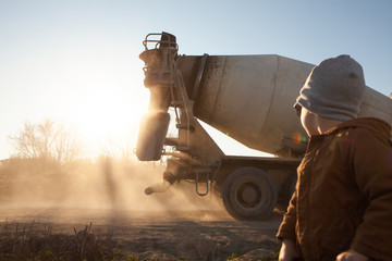 Construction equipment. A concrete mixer is driving along a country road. 
