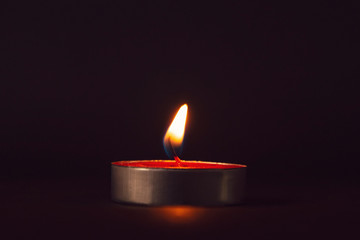 Single candle burning in the dark