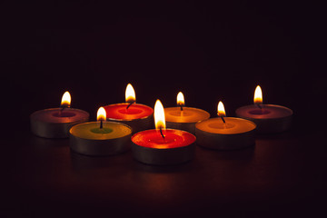 Group of colorful candles burning in the dark