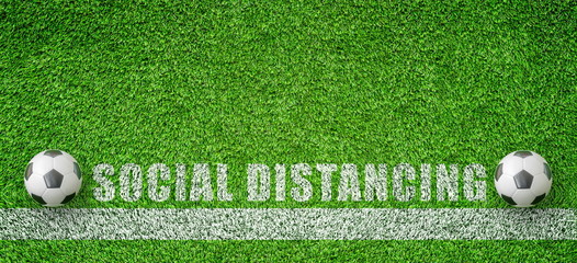 CORONA Virus and Social Distancing Concept : Two soccer balls put on green artificial grass that keeping distance for social distancing campaign.