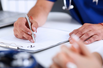 Male doctor hand write prescription at office worktable using silver pen. Panacea, life save,...
