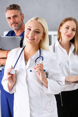 Fototapeta premium Group of medics proudly posing in row and looking in camera smiling. High level service, best treatment, 911, professional, healthy lifestyle, therapeutist consultation, physical, emergency concept