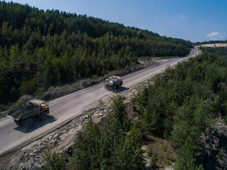 Obraz na płótnie Canvas Huge industrial dumpers stone quarry transporting marble shot from drone chase