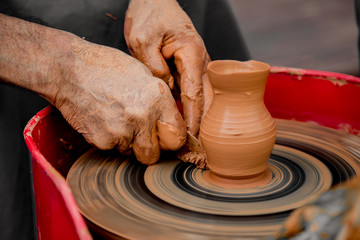 Hands of the potter. The potter makes pottery dishes on potter's wheel. The sculptor in workshop makes clay product closeup