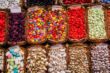Sweets dragees of different colors and tastes in wicker trays with labels.